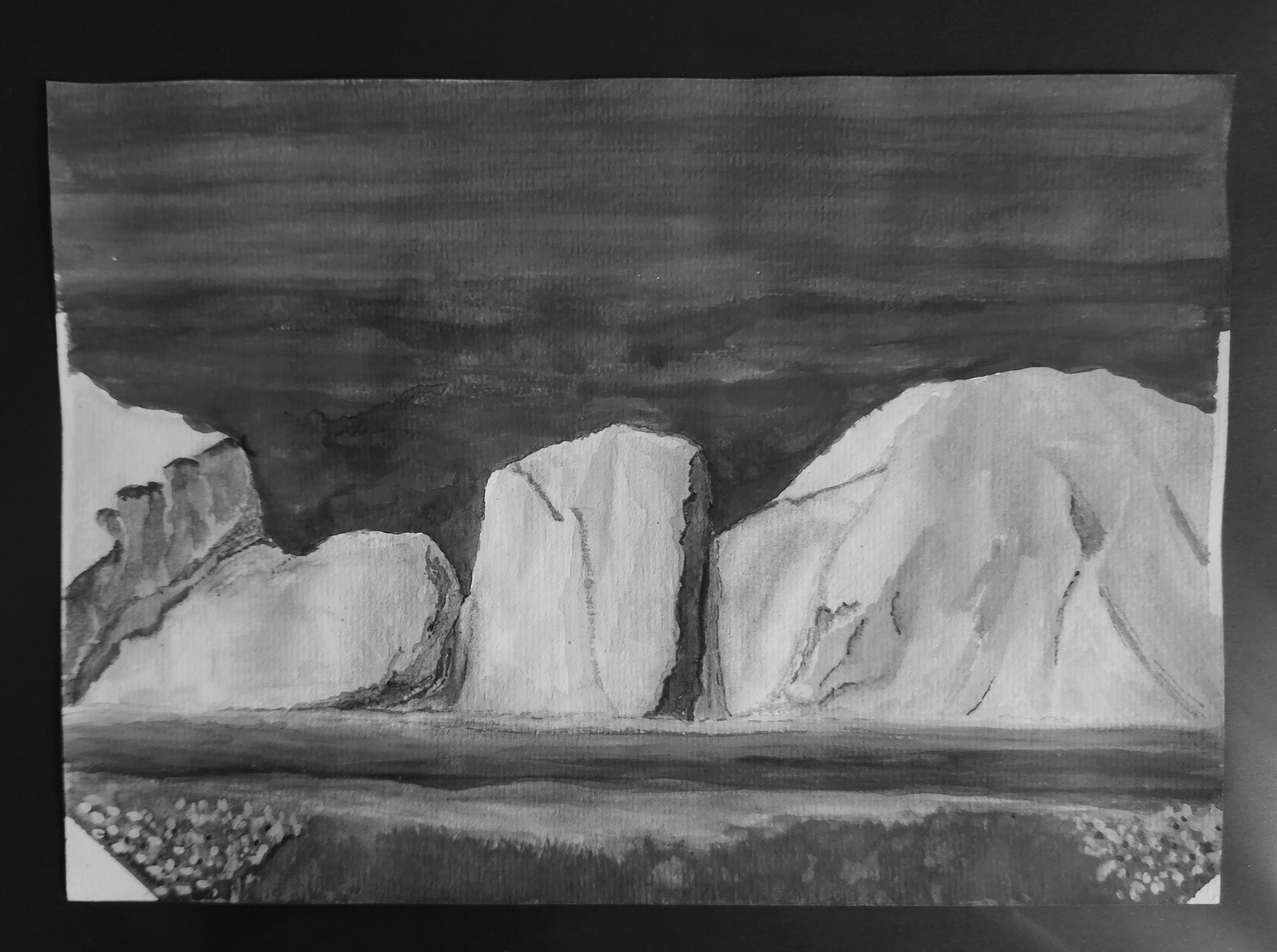 Monochrome watercolor landscape of coastal cliffs rising from calm water beneath a dark sky, with wildflowers along the foreground shore.